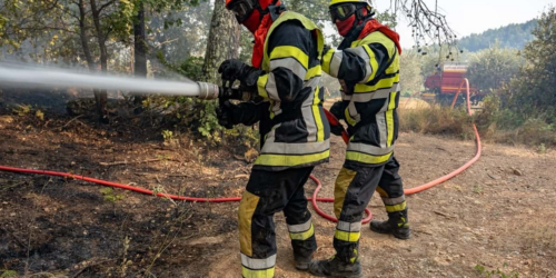Pompiers en tenue de protection tenant un tuyau